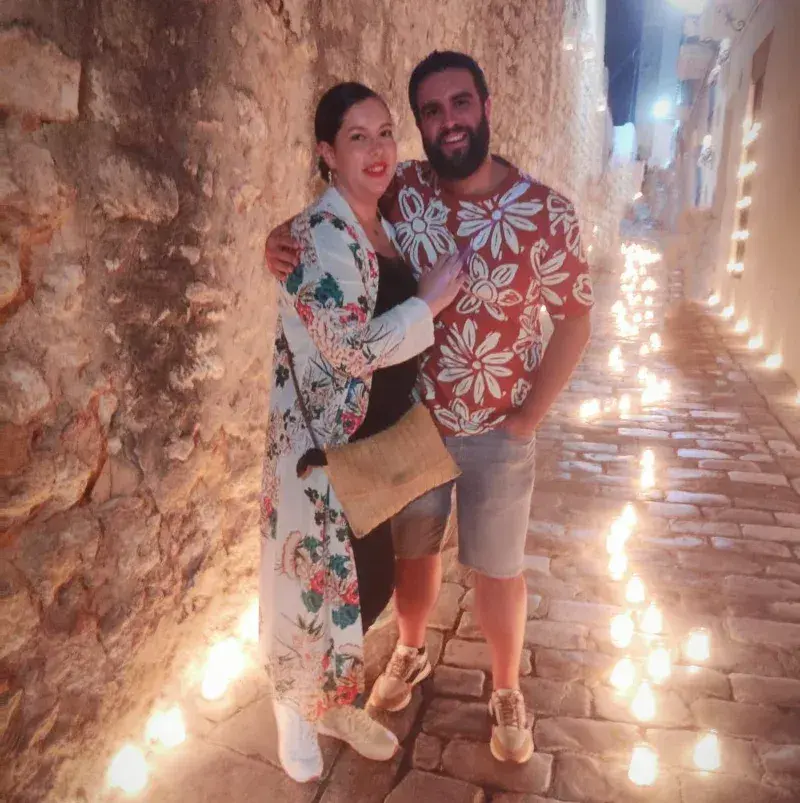 Amaranto y Mireya abrazados en una calle con velas en el suelo